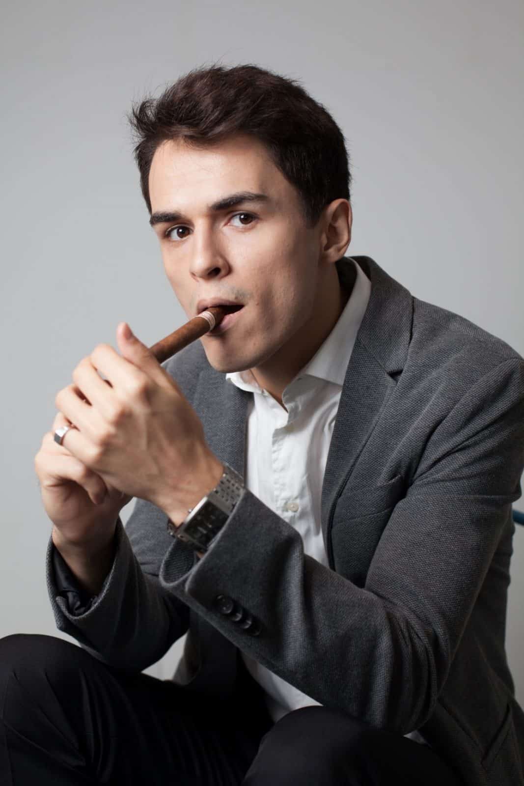 A man lighting a cigar practices common cigar etiquette.