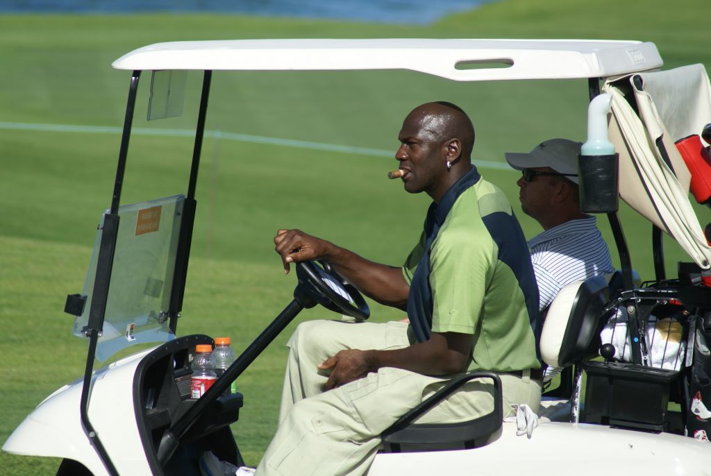 Michael Jordan smoking a cigar while driving a golf cart.