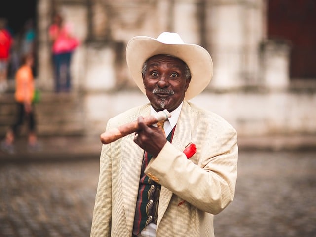 The history of cigars stretches far and wide. Pictured here, a man in a white suit holding a jumbo cigar.