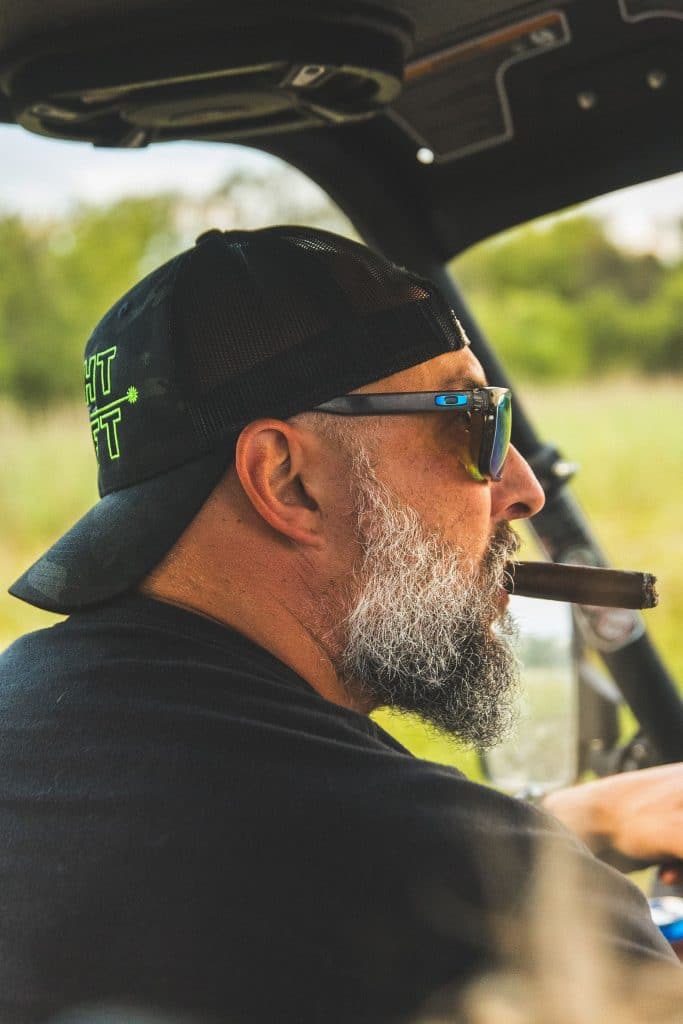 Jon Simons smoking a cigar in a car.